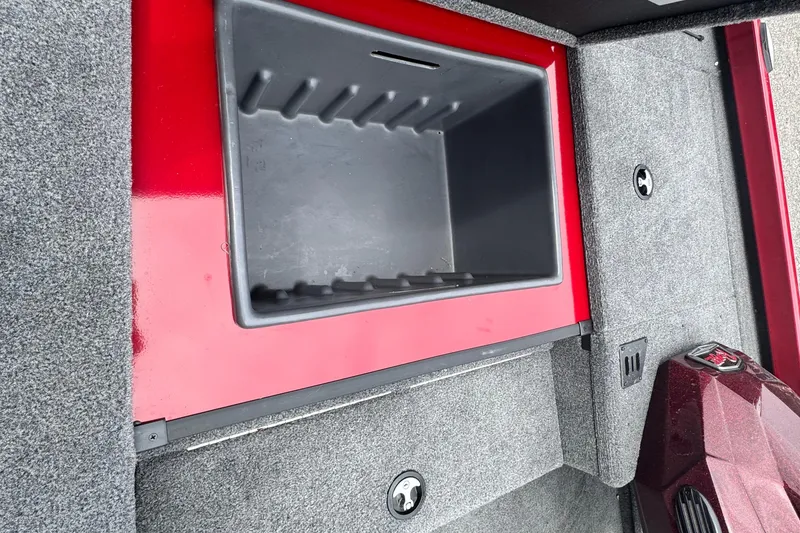 Slide: The Image of 2024 Bass Tracker RT178 storage compartment with red trim and gray carpet interior. - 21