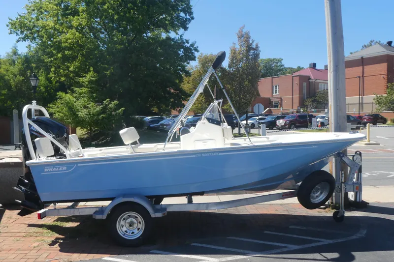 Slide: The Image of 2026 Boston Whaler 170 Montauk boat on trailer, parked outdoors in a sunny setting. - 2