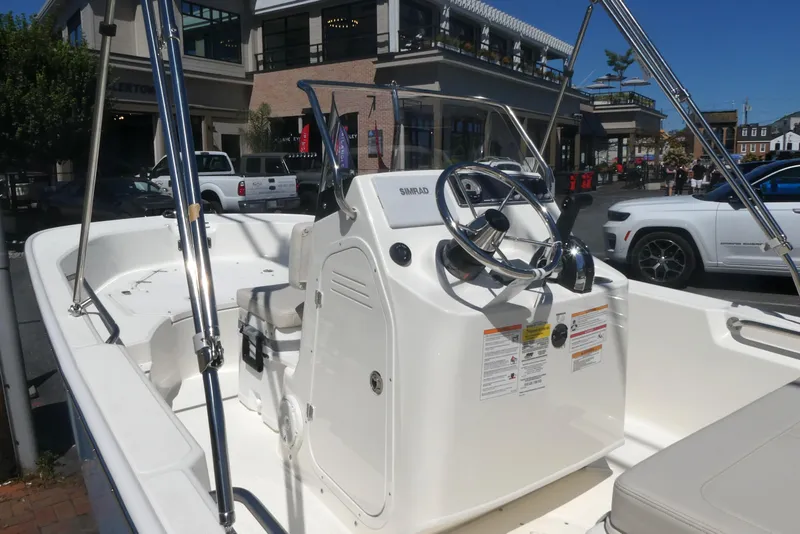 Slide: The Image of 2026 Boston Whaler 170 Montauk boat interior with steering console, parked in urban setting. - 9