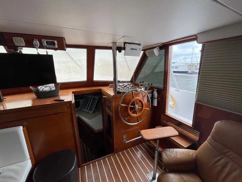 Slide: The Image of 1985 DeFever 40 Offshore Cruiser interior with helm, wooden accents, and comfortable seating. - 11