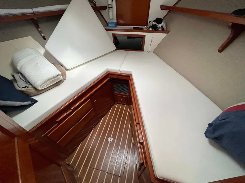 Slide: The Image of 1985 DeFever 40 Offshore Cruiser cabin with wooden flooring and white cushioned seating. - 17