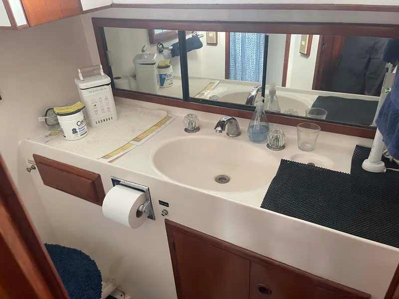 Slide: The Image of 1985 DeFever 40 Offshore Cruiser bathroom with sink, mirror, and toiletries. - 25