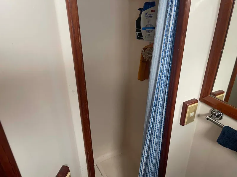 Slide: The Image of 1985 DeFever 40 Offshore Cruiser shower area with wooden trim and blue-striped curtain. - 26