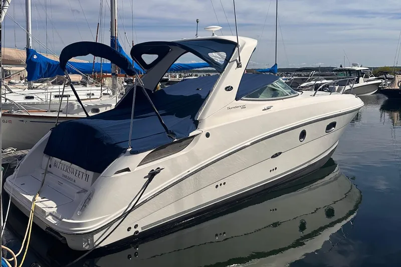 The Image of 2010 Sea Ray 310 Sundancer yacht docked in a marina, featuring sleek design and blue canopy. - 0