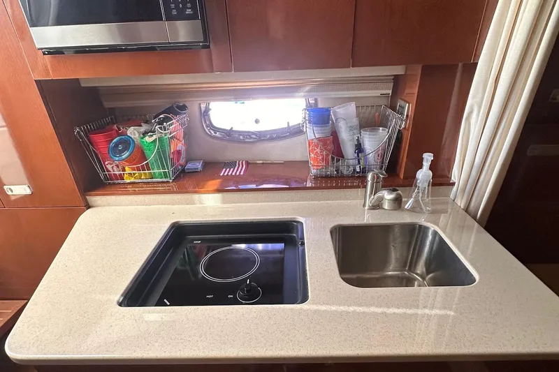 Slide: The Image of 2010 Sea Ray 310 Sundancer kitchen with stove, sink, and storage baskets. - 9