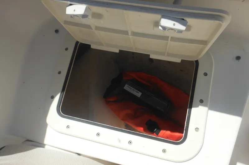 Slide: The Image of Open storage compartment on 2000 Boston Whaler 18 Ventura Bowrider, containing an orange life jacket. - 16