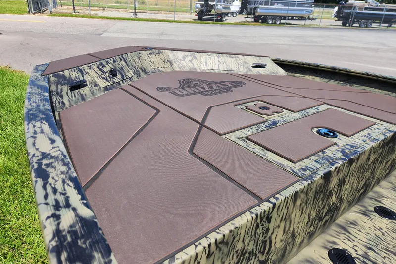 Slide: The Image of 2026 Tracker Grizzly 1860 CC boat deck with camouflage design, parked outdoors. - 8