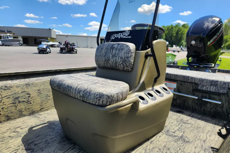 Slide: The Image of 2026 Tracker Grizzly 1860 CC boat interior with camo seating and console, outdoors. - 9