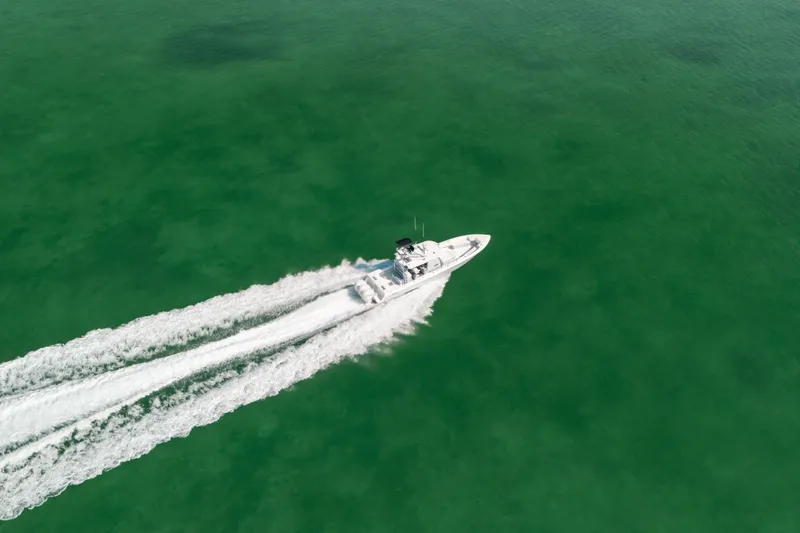 Slide: The Image of Aerial view of 2025 Contender 44 ST boat cruising on clear green water. - 1