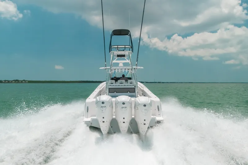 Slide: The Image of 2025 Contender 44 ST boat cruising on open water, rear view with triple engines. - 3