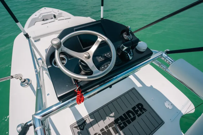 Slide: The Image of Helm of 2025 Contender 44 ST boat with steering wheel and controls on turquoise water. - 30