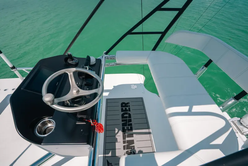 Slide: The Image of 2025 Contender 44 ST boat helm with steering wheel and seating, overlooking turquoise water. - 31