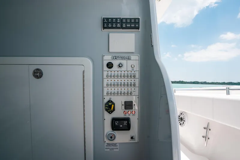 Slide: The Image of Control panel on 2025 Contender 44 ST boat, featuring switches and gauges, with ocean view. - 36