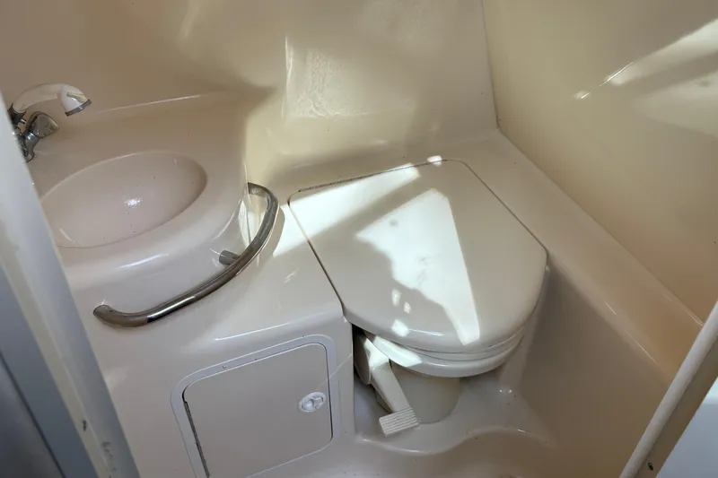 Slide: The Image of 1998 Sea Ray 290 Sundancer bathroom with sink and toilet, compact marine design. - 12