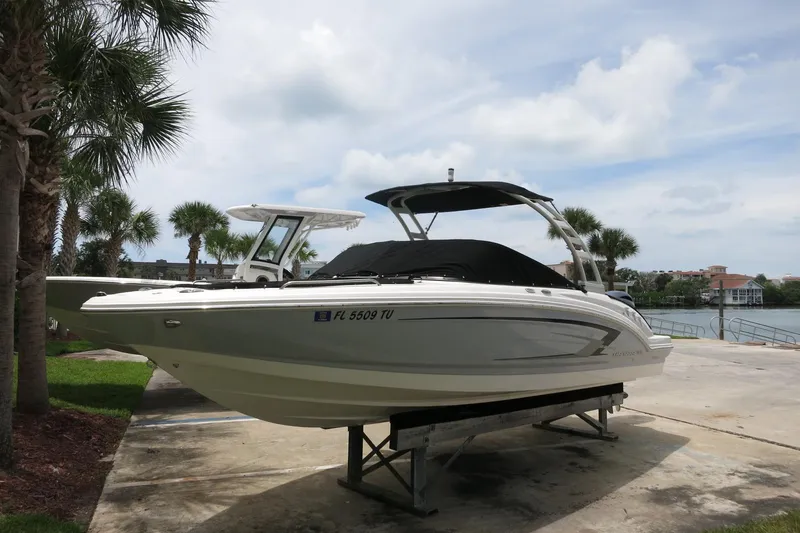 Slide: The Image of 2023 Chaparral 23 SSi OB boat on display, surrounded by palm trees and waterfront scenery. - 2