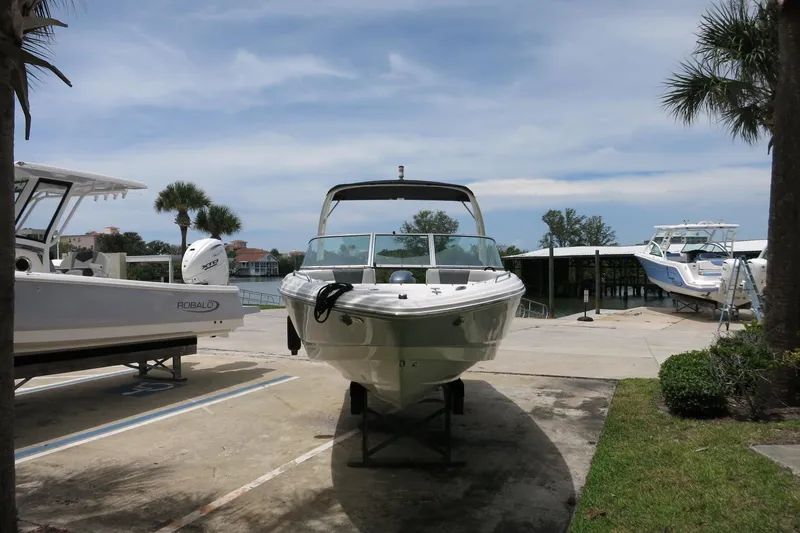 Slide: The Image of 2023 Chaparral 23 SSi OB boat displayed outdoors near water and palm trees. - 42