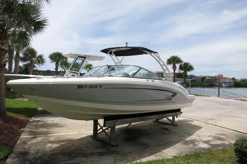 Slide: The Image of 2023 Chaparral 23 SSi OB boat on trailer, surrounded by palm trees and waterfront view. - 43