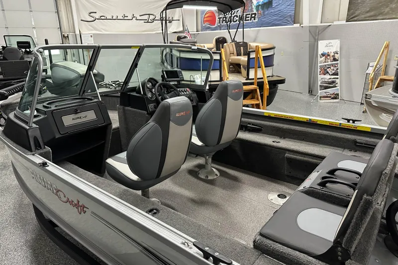 Slide: The Image of 2020 Alumacraft Classic 165 Sport boat interior with seating and dashboard in showroom. - 12