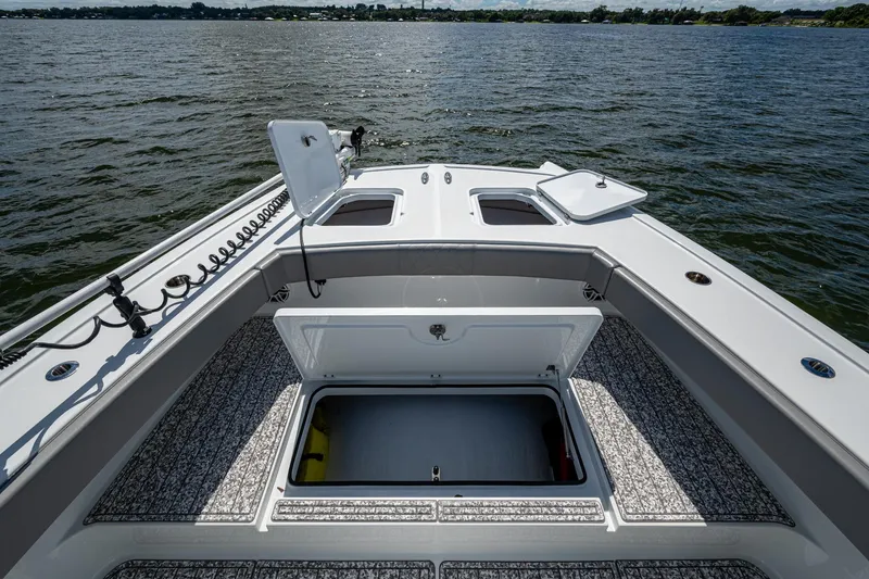 Slide: The Image of 2022 Freeman 34VH boat deck with open storage compartments on a calm lake. - 34