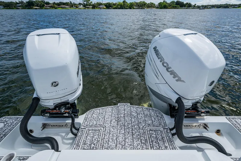 Slide: The Image of Twin Mercury outboard engines on a 2022 Freeman 34VH boat, cruising on a lake. - 54