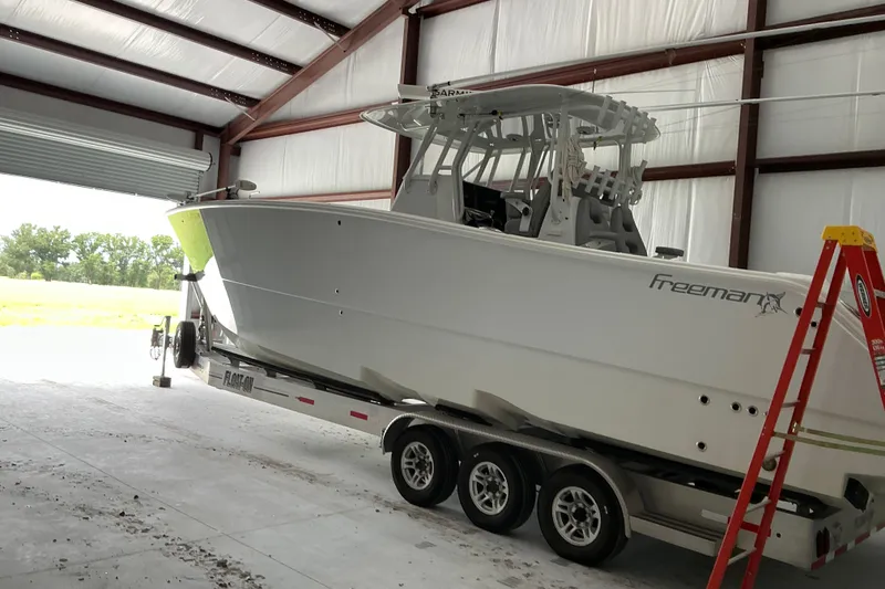 Slide: The Image of 2022 Freeman 34VH boat on trailer inside a metal garage with open door. - 65