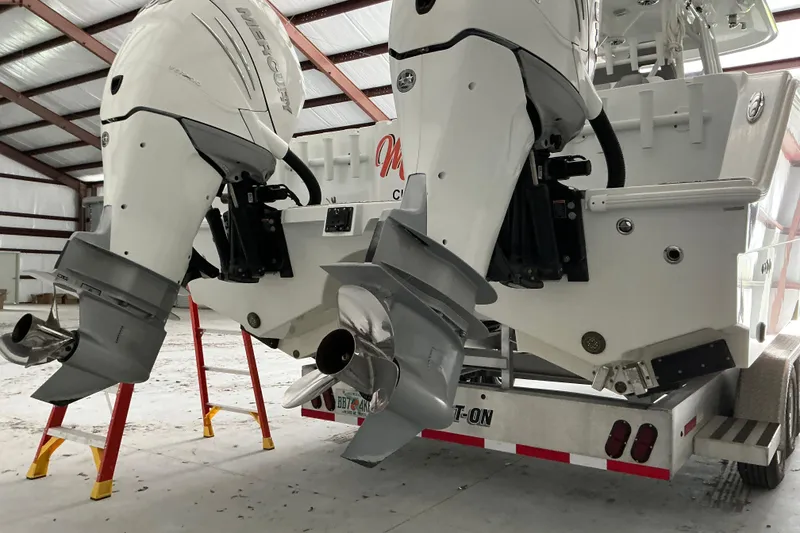 Slide: The Image of Twin Mercury outboard engines on a 2022 Freeman 34VH boat in a warehouse setting. - 69