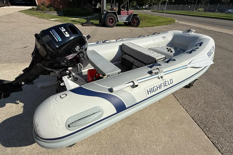 Slide: The Image of 2020 Highfield Classic 310 inflatable boat with Suzuki outboard motor on a driveway. - 2