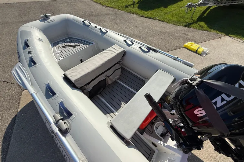 Slide: The Image of 2020 Highfield Classic 310 inflatable boat with Suzuki outboard motor on pavement. - 4
