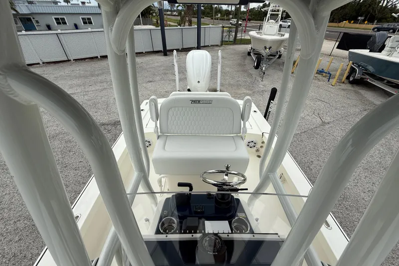 Slide: The Image of 2026 Pathfinder 2300 HPS boat interior with steering console and seating, parked outdoors. - 21