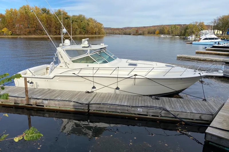 Slide: The Image of 1996 Tiara 4300 Open yacht docked on a serene lake with autumn foliage. - 5