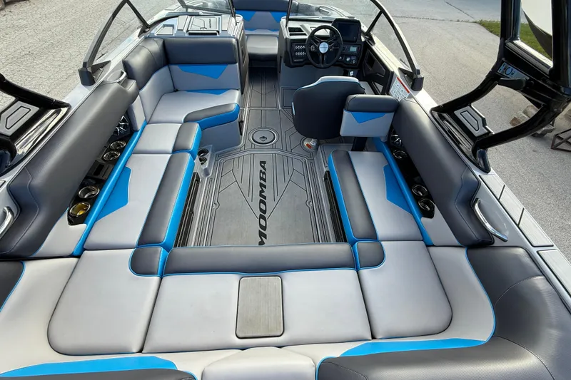 Slide: The Image of 2022 Moomba Kaiyen boat interior with gray and blue seating, modern dashboard. - 2