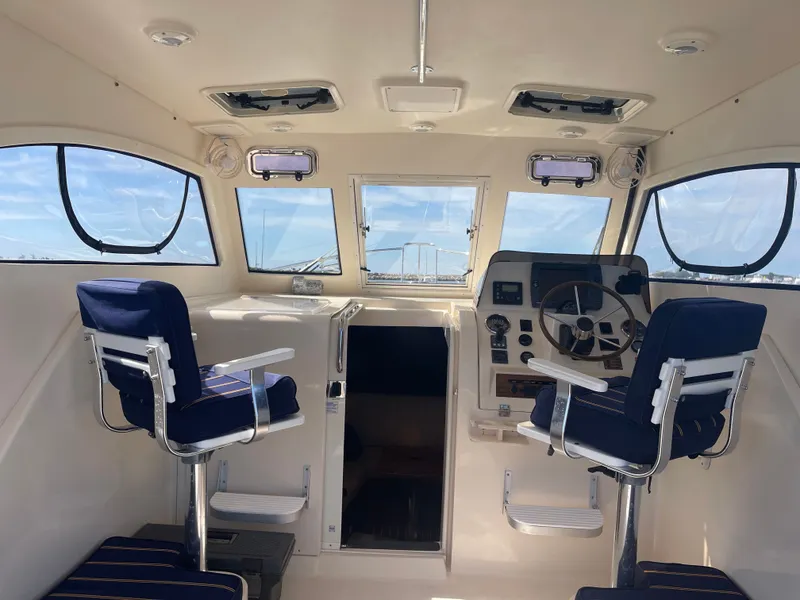 Slide: The Image of 2005 Mainship Pilot 30-II boat interior with helm, blue seats, and large windows. - 15