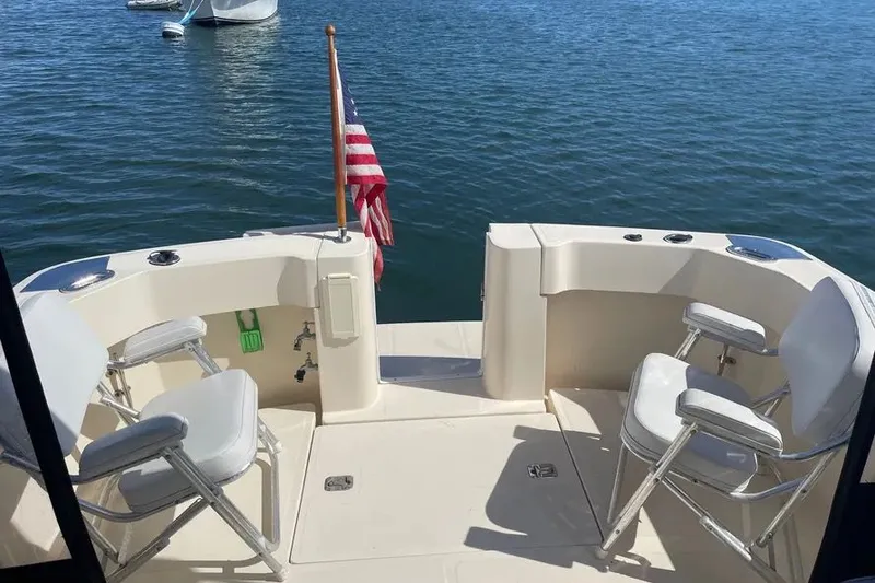 Slide: The Image of 2005 Mainship Pilot 30-II boat deck with chairs and American flag on water. - 17