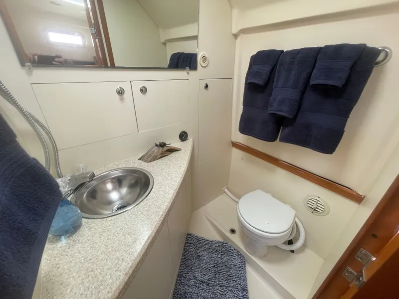 Slide: The Image of 2005 Mainship Pilot 30-II bathroom with sink, toilet, and navy towels. - 31
