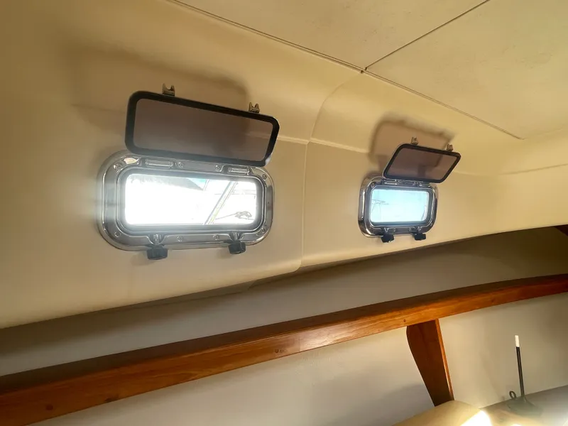 Slide: The Image of 2005 Mainship Pilot 30-II cabin interior with open portholes and wooden trim. - 40