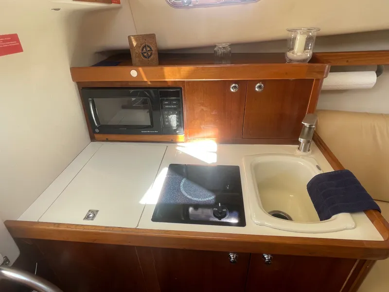 Slide: The Image of 2005 Mainship Pilot 30-II galley with microwave, stove, and sink. - 48