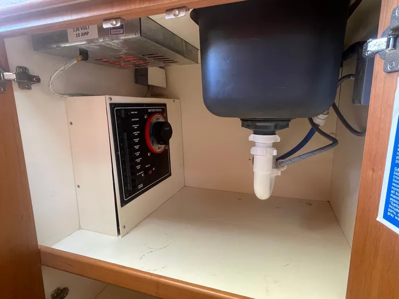 Slide: The Image of 2005 Mainship Pilot 30-II electrical panel and plumbing under sink. - 49