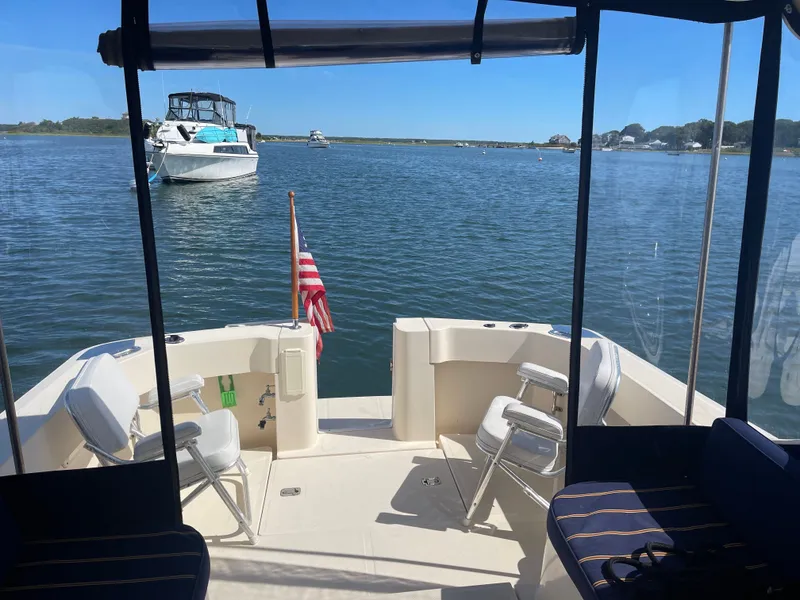 Slide: The Image of 2005 Mainship Pilot 30-II boat interior with chairs, American flag, and scenic water view. - 8