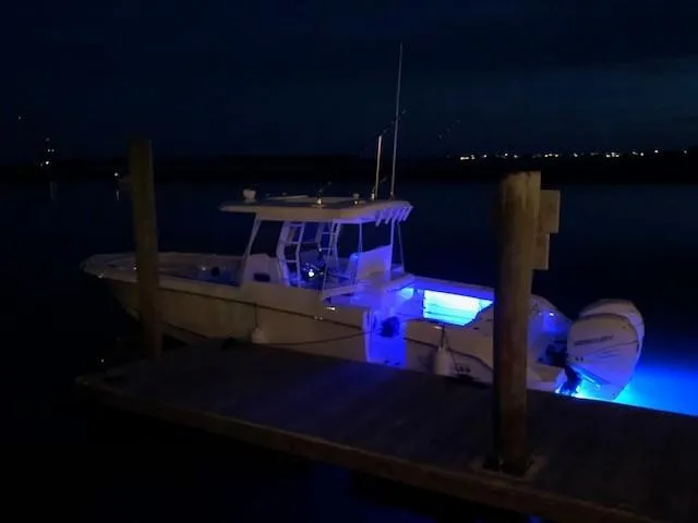 Slide: The Image of 2017 Boston Whaler 330 Outrage boat docked at night with blue LED lights. - 10