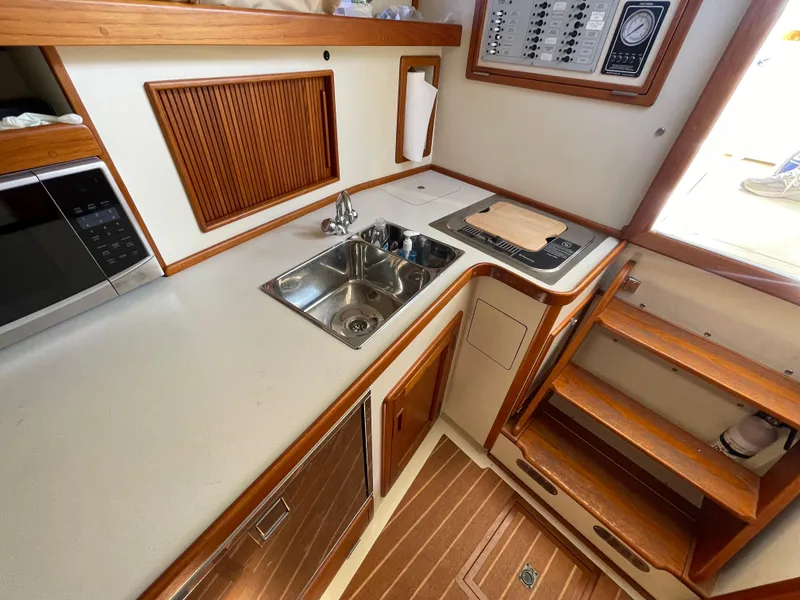 Slide: The Image of 2015 Fortier 30 boat kitchen with sink, stove, and wooden cabinetry. - 19