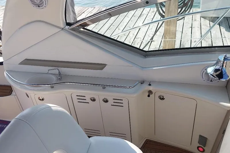 Slide: The Image of 2004 Sea Ray 420 Sundancer interior with sink and storage, docked by wooden pier. - 10