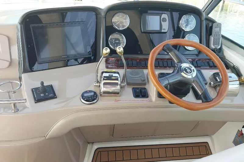 Slide: The Image of 2004 Sea Ray 420 Sundancer helm with wooden steering wheel and navigation controls. - 4