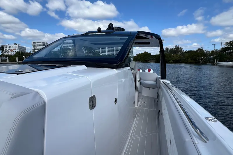 Slide: The Image of 2025 Cigarette 41 Nighthawk boat on water, sleek design, clear sky, modern architecture. - 36