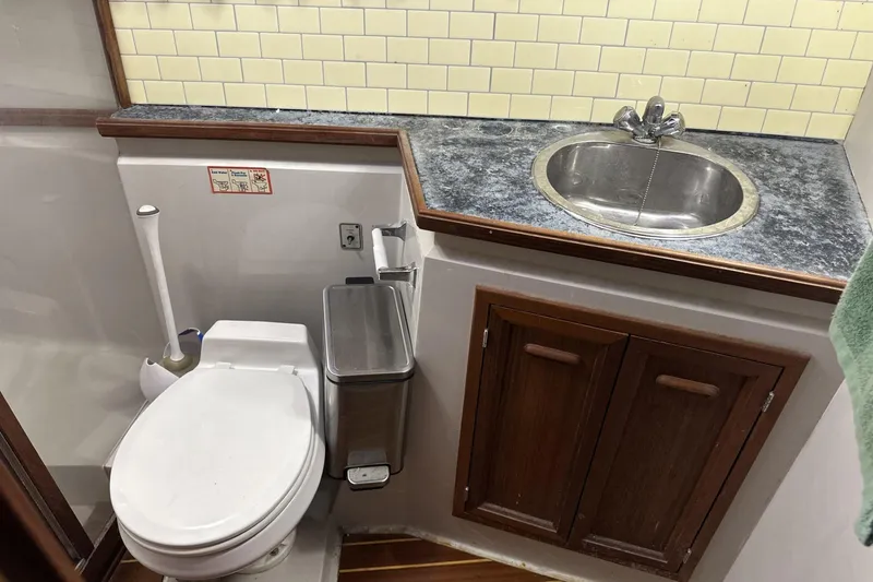 Slide: The Image of 1986 Carver 42 Aft Cabin Motoryacht bathroom with toilet, sink, and storage cabinets. - 24