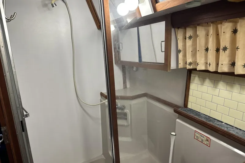 Slide: The Image of 1986 Carver 42 Aft Cabin Motoryacht bathroom with shower, mirror, and star-patterned curtains. - 25