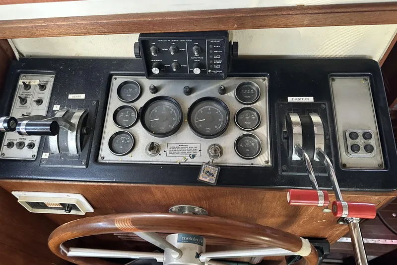 Slide: The Image of 1986 Carver 42 Aft Cabin Motoryacht helm with gauges, controls, and wooden steering wheel. - 30
