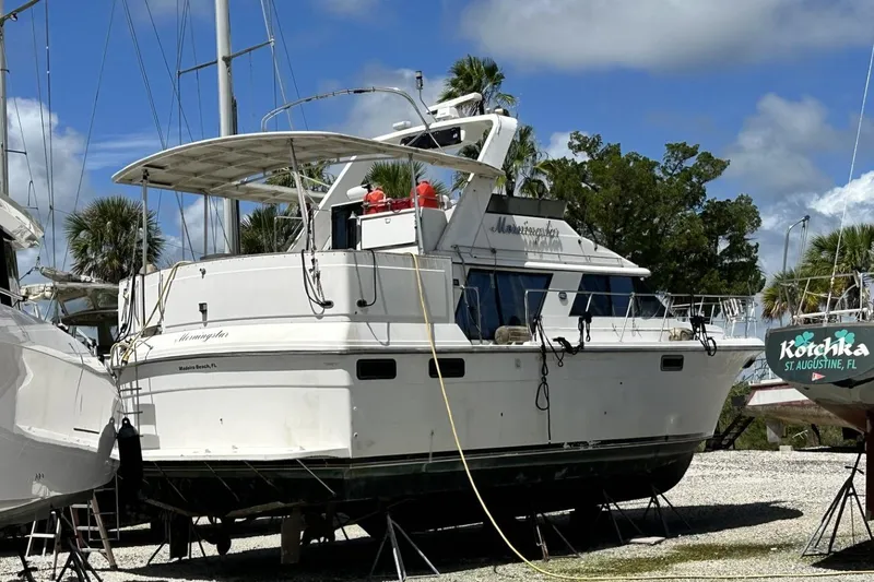 Slide: The Image of 1986 Carver 42 Aft Cabin Motoryacht on dry dock, surrounded by trees and other boats. - 4