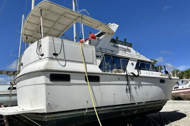 Slide: The Image of 1986 Carver 42 Aft Cabin Motoryacht on land, white exterior, clear blue sky. - 6