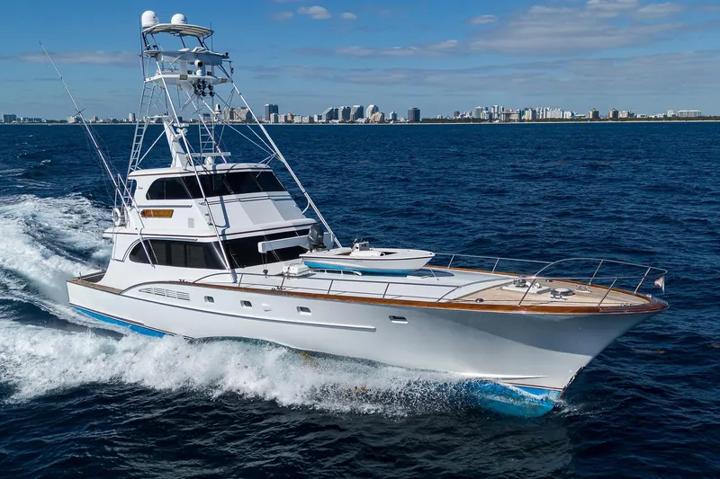 Slide: The Image of 1985 Feadship Yacht Fisherman cruising on open sea with city skyline in background. - 0