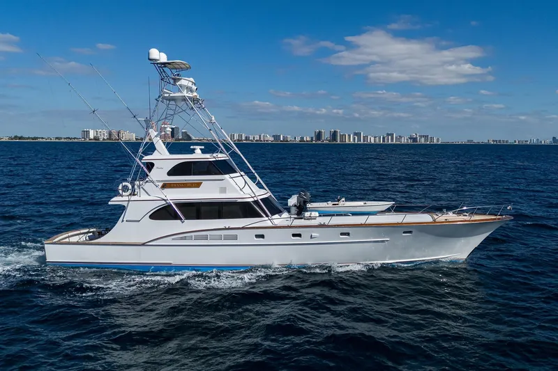 Slide: The Image of 1985 Feadship Yacht Fisherman cruising on open sea with city skyline in background. - 1